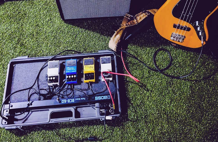 Shows a bunch of cables connected to a bass and a bunch of stompbox effects