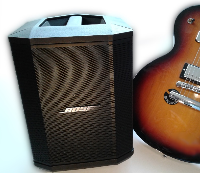 The Bose S1 Pro, set next to a Gibson Les Paul for a size comparison.